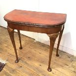 A 1930s walnut card table, the demi lune foldover top with baize lined interior, raised on shell