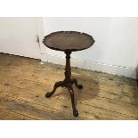 A pedestal low wine table, with scalloped top, raised on turned fluted column and tripod carved