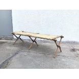 A WWII folding camp bed raised on folding triple X frame supports, with original canvas cover (a/