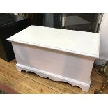 A white painted blanket/toy box, the rectangular hinged top enclosing a plain interior, raised on