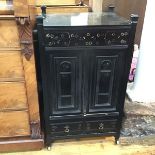 A modern ebonised cabinet with single slide panelled door, over a single fall front cupboard, on
