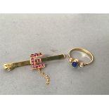 A yellow metal bar brooch with figure E mounted with pink stones (2g) and a yellow metal ring