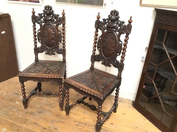 A pair of 19thc oak hall chairs, with surmounted plumed helmet and visor, with oval relief carved