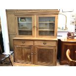 A 19thc two part pine kitchen dresser with moulded cornice and twin glazed panel doors to top with