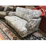 A modern Ikea two seater sofa upholstered in grey and white floral pattern fabric, complete with