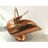 An Edwardian copper coal scuttle with arched adjustable handle, complete with copper shovel with