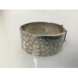 An early 20thc Chester silver bangle with clasp, one side engraved with leaf decoration (3cm x 6cm x