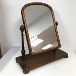 A late Victorian mahogany dressing table mirror, the hinged domed glass between two turned supports,