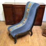A late Victorian ebonised nursing chair, the upholstered back and seat with central fruit and flower