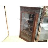 An Edwardian mahogany corner cupboard with blind carved frieze and glazed astragal panel door