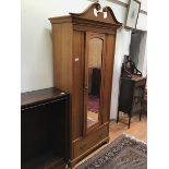 A Victorian pine wardrobe, with broken scroll pediment over a single mirrored door, the interior