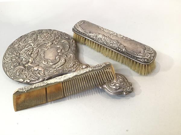 A Birmingham silver three piece associated dressing table brush set comprising winged cherub and C