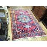 A handknotted rug, the red field with central medallion surrounded by a border of stylised