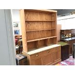 A 19thc stripped pine two part dresser, the moulded top above four open shelves, three frieze