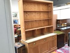 A 19thc stripped pine two part dresser, the moulded top above four open shelves, three frieze