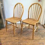 A pair of Ercol light ash spindle back kitchen chairs with shaped wood saddle seats, on turned