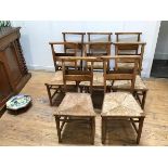 A set of eight Edwardian chapel chairs, each with a book rack to back and rush seat (85cm x 53cm x