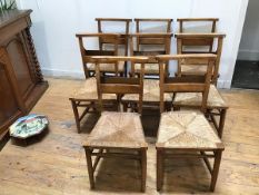 A set of eight Edwardian chapel chairs, each with a book rack to back and rush seat (85cm x 53cm x