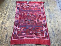 A kelim rug, with geometric and animal design, red field, areas of wear and tear, attached to slat