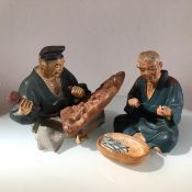 A pair of Japanese pottery decorated polychrome seated figures of a Fisherman and Stone Carver (h.