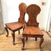 A pair of Swiss style 19thc pine hall chairs, with edelweiss carved arched tops, with shaped wood