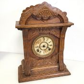 An oak mantel clock with moulded dome top above a dial with roman numerals, door to reverse with