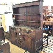 A George III elm two part dresser with plate rack back, the moulded cornice above three open