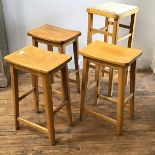 A set of three ash saddle shaped mid century stools with rectangular tops on square moulded supports