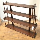 An Edwardian mahogany four tier graduated wall shelf, each shelf raised on turned tapered columns