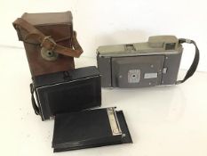 A Zeiss Ikon camera (8cm x 12cm x 4cm) with leather carry case, and a Polaroid Land Camera (2)
