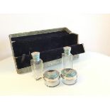 A 1930s travelling case with velvet lined interior containing two ointment bottles and two dishes