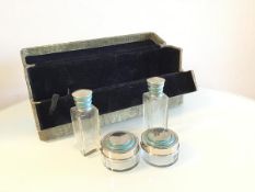 A 1930s travelling case with velvet lined interior containing two ointment bottles and two dishes