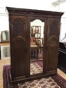 An Edwardian mahogany gentleman's wardrobe with a central mirror and moulded panelled door, with