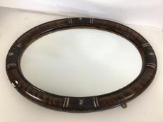 An Edwardian oval mirror with metal mounts (58cm x 43cm) (a/f)