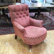 A modern low library armchair with button back, upholstered in a stylised flowerhead fabric, with