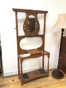 An Arts & Crafts hallstand, the top with oval mirror over a shelf, with two stick stands, complete