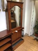 A modern cherrywood hallstand, with bevelled domed mirror above stick rail and drip pan, on plinth