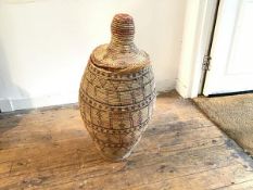 An African coloured straw woven upright basket, with hooded top, of tapered cylinder form (h.77cm)