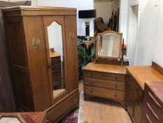 An Edwardian oak three piece bedroom suite comprising a wardrobe fitted single door above a frieze