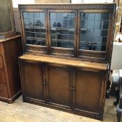 A 1920s two part oak bookcase, the upper tier with three glazed doors, with moulded frieze, with