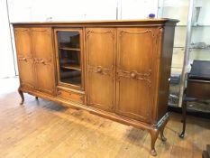 A German walnut low cabinet, the rectangular moulded top with centre glazed panel door above a