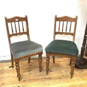 A pair of late Victorian side chairs with turned spindle backs above green upholstered seats, on