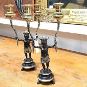 A pair of reproduction bronzed figure twin branch candlesticks in the Regency style, raised on