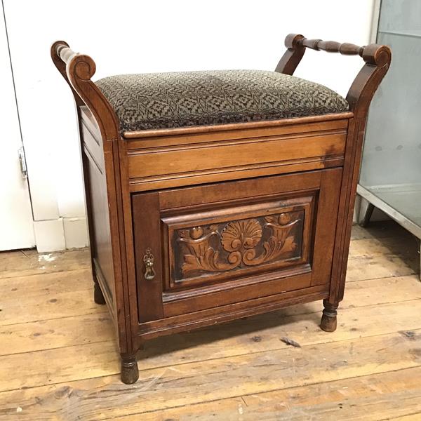 An Edwardian piano stool with upholstered hinged seat above a music recess, with turned side