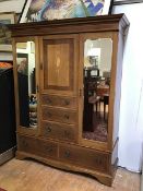 An Edwardian mahogany wardrobe with central cabinet fitted hanging pegs above three graduated