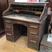 A 1920s oak kneehole desk, with tambour roll top and fitted interior with pigeon holes and two