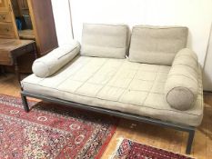 A large modern ottoman with two cushions and two bolsters upholstered in a grey textured fabric,