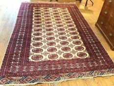 A Bokhara rug, the centre panel with four rows of thirteen stylised medallions enclosed within a