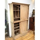 A Victorian stripped pine two section cabinet, each with a pair of sliding doors and fitted interior