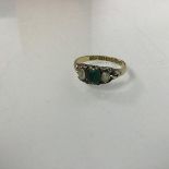 A 15ct gold three stone ring, with central emerald flanked by a pair of near colourless stones (M)